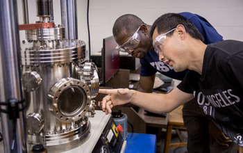 Two students in front of a high-temperature high-vacuum molding system
